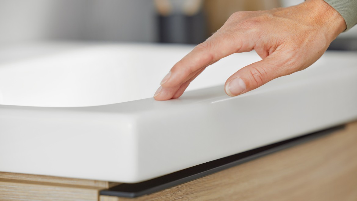 Macro image of a hand touching a washbasin in white matte