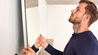 Man hanging up a mirror during a bathroom renovation